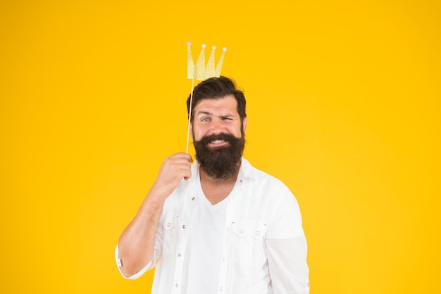 Handsome bearded guy king Guy in yellow background posing with booth props Photo booth fun Bearded man king costume party King of party Costume party Holiday carnival celebration Birthday boy
