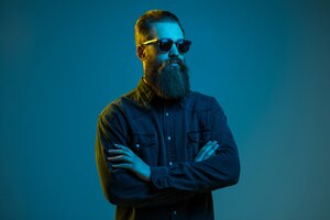 Handsome bearded hipster man wearing round sunglasses isolated over blue light space
