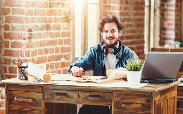 Photo handsome bearded male architect working on a building plan at his desk smiling to the camera joyfully copyspace professionalism trustworthy qualified experienced engineer constructionist developer