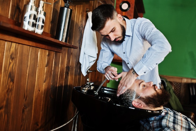 Foto bell'uomo barbuto al barbiere barbiere al lavoro lavare la testa