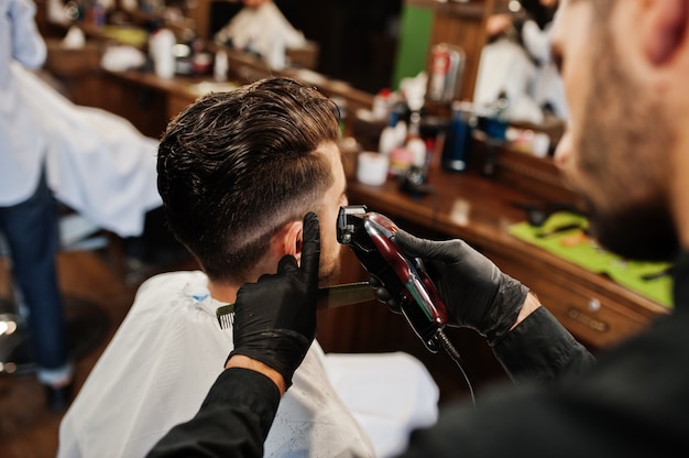 Handsome bearded man at the barbershop, barber at work.