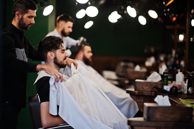 Handsome bearded man at the barbershop barber at work