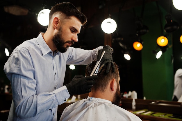 Handsome bearded man at the barbershop barber at work