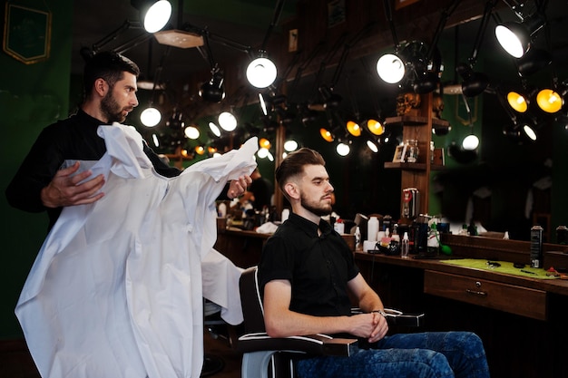 Handsome bearded man at the barbershop barber at work