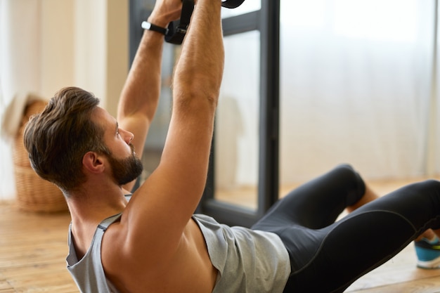 Красивый бородатый мужчина делает упражнения с эластичной лентой для фитнеса