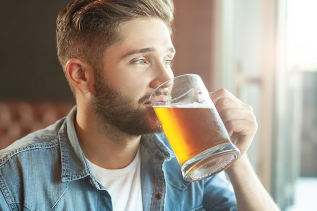 Красивый бородатый мужчина пьет пиво в кафе