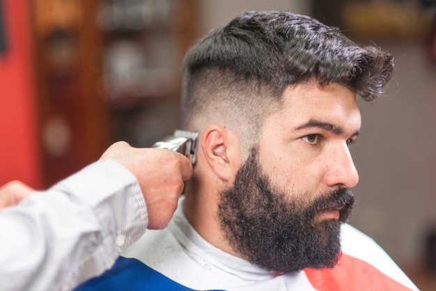 Handsome bearded man, getting haircut by barber