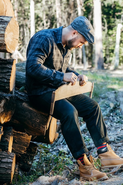 Uomo barbuto bello vicino a tronchi di legno