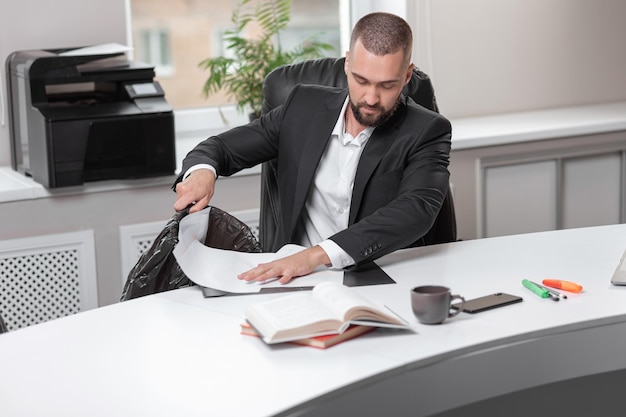 Handsome bearded man in office business suit throws out garbage