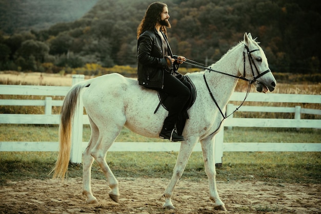 Handsome bearded man riding horse at farm beautiful horse with man rider trotting on autumnal field