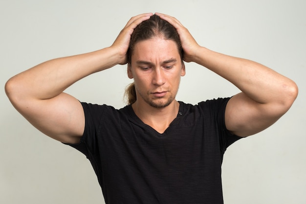  handsome bearded man with long hair against white wall