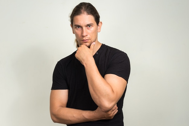  handsome bearded man with long hair against white wall