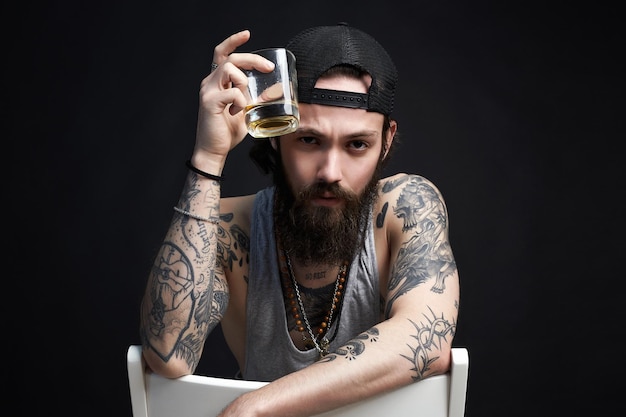 Foto bell'uomo barbuto con tatuaggio che si gode il whisky