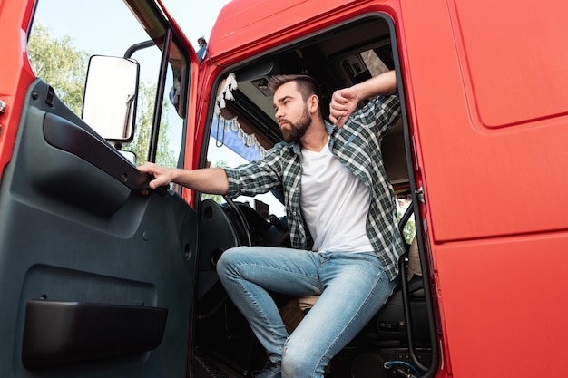 Красивый бородатый водитель грузовика внутри своего красного грузовика