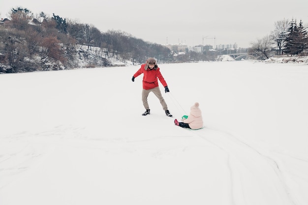 Handsome bearded young dad and his little cute daughter are having fun outdoor in winter Enjoying spending time together Family concept