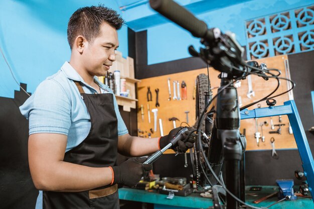 Handsome bicycle mechanic using a high pressure bike pump to adjust shock absorbers