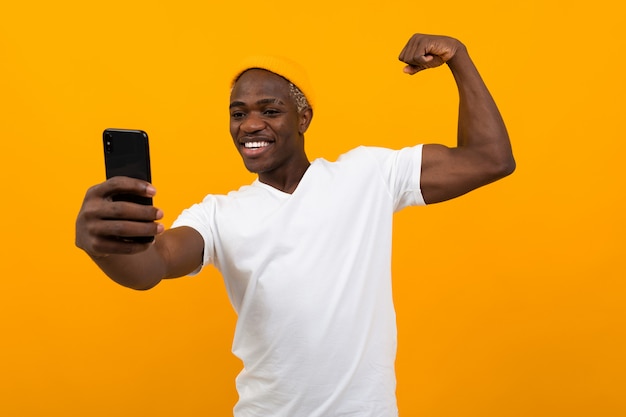 Handsome black american man taking selfie on phone over orange with copy space