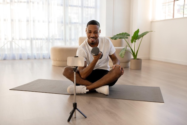 Handsome black guy fitness blogger streaming while exercising with barbell