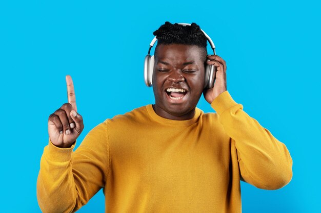 Handsome black guy in wireless headphones listening music and singing