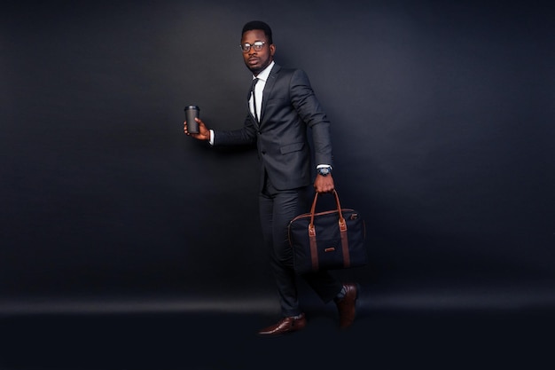 Handsome black successful and rich american businessman in dark\
suit. studio fashion shot full height isolated on black\
background.