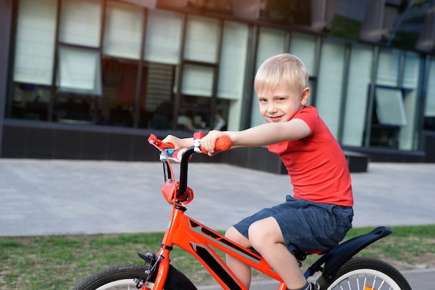 Handsome blond boy rides on a children's bicycle