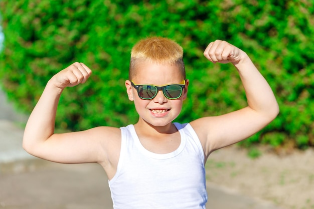 Handsome blond boy in white t-shirt shows muscles