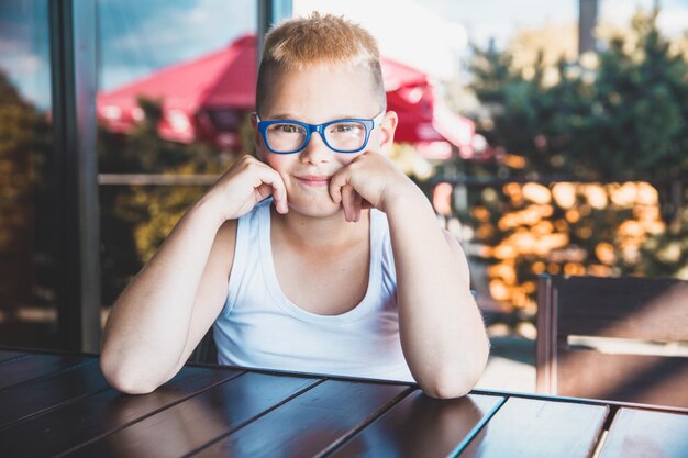 Handsome blond boy with glasses in a restaurant drinking coffee