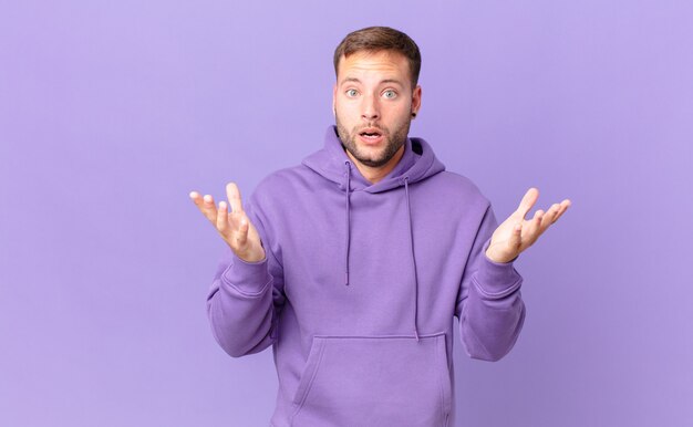 Handsome blonde man feeling extremely shocked and surprised