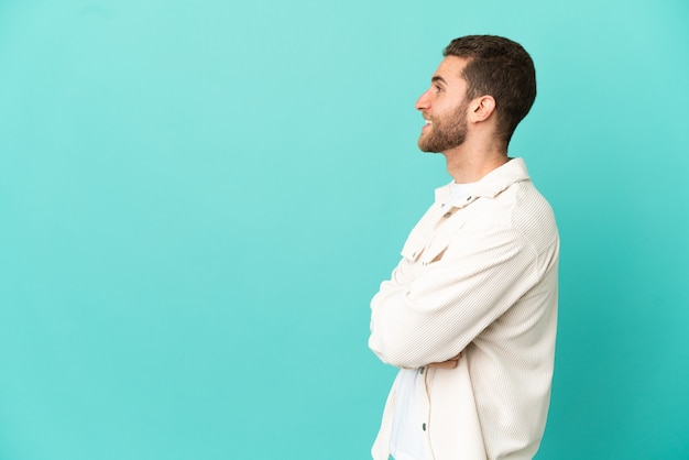 Handsome blonde man over isolated blue background in lateral position