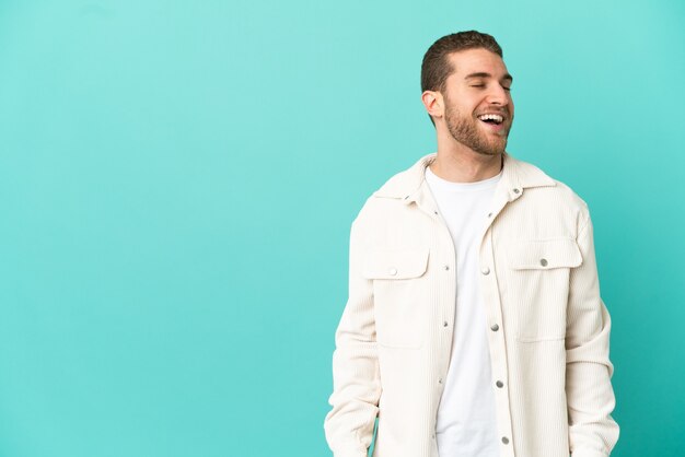 Handsome blonde man over isolated blue background laughing