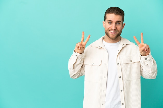 Handsome blonde man over isolated blue background showing victory sign with both hands