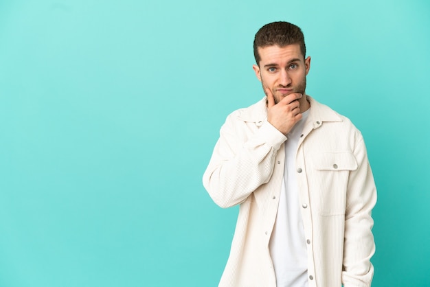 Handsome blonde man over isolated blue background thinking