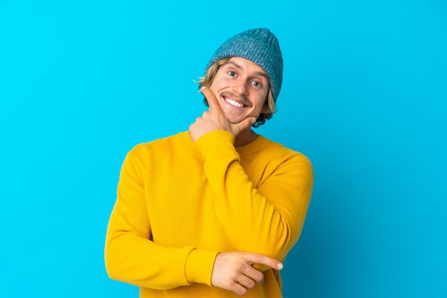 Handsome blonde man isolated on blue happy and smiling