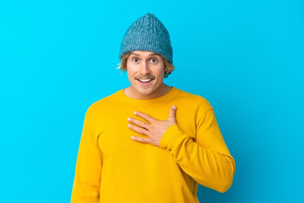 Handsome blonde man isolated on blue wall pointing to oneself