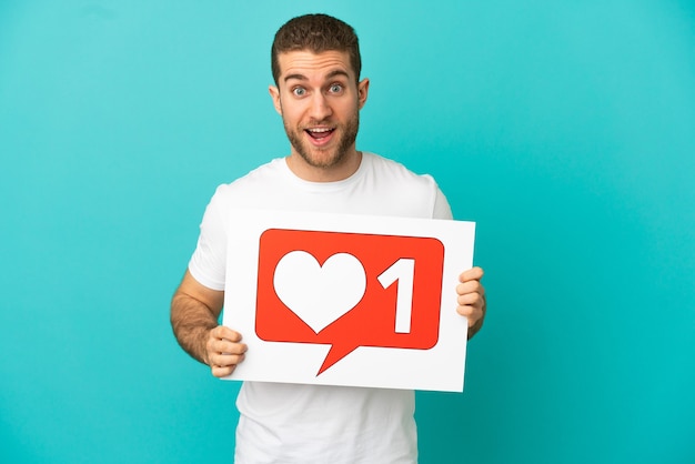 Photo handsome blonde man isolated holding a placard with like icon with happy expression