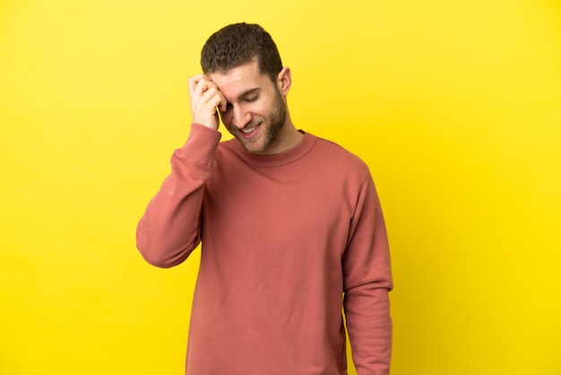 Handsome blonde man over isolated yellow background laughing