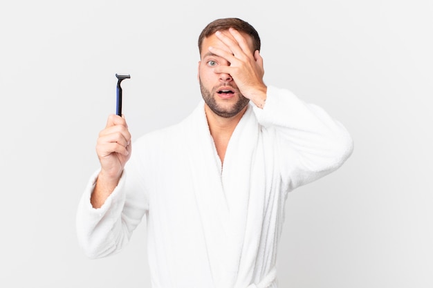 Handsome blonde man looking shocked, scared or terrified, covering face with hand. shaving concept