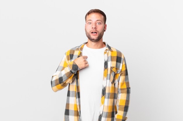 Handsome blonde man looking shocked and surprised with mouth wide open, pointing to self