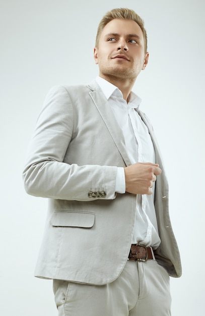 Handsome blonde man model in a fashion gray suit in studio