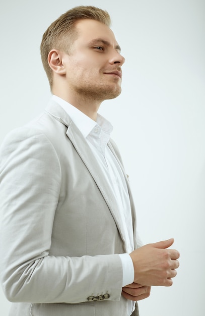 Handsome blonde man model in a fashion gray suit in studio