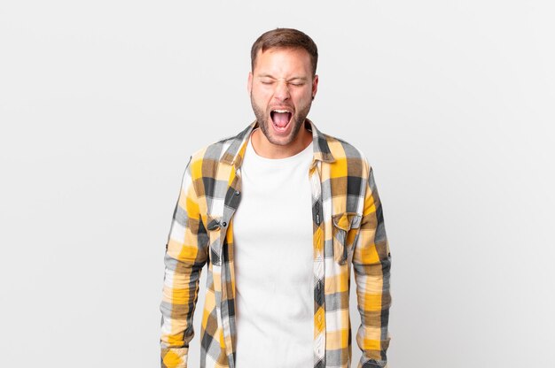 Handsome blonde man shouting aggressively, looking very angry