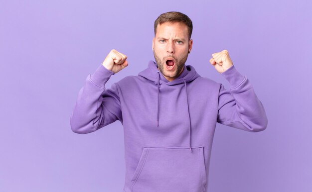 Handsome blonde man shouting aggressively with an angry expression