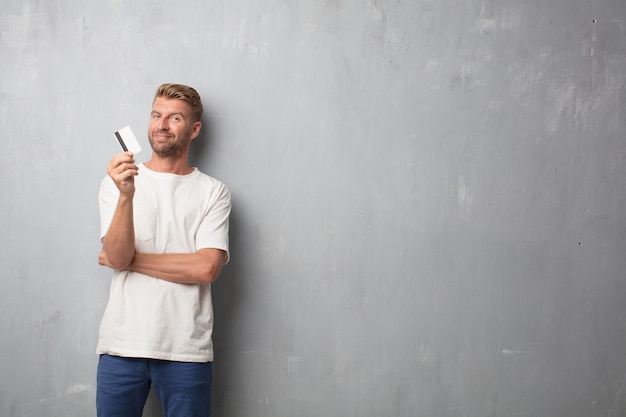 Handsome blonde man with a credit card over a grunge wall textur