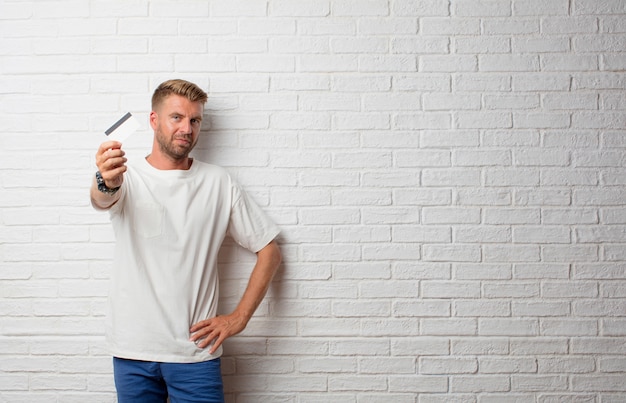 Handsome blonde man with a credit card over a grunge wall