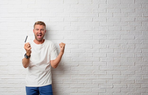 Handsome blonde man with a credit card over a grunge wall