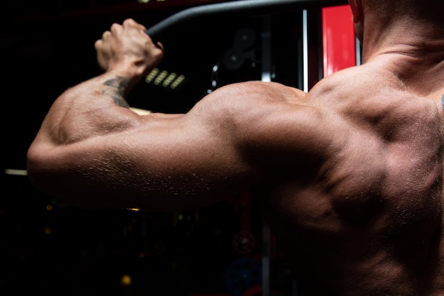 Photo handsome bodybuilder doing heavy weight exercise for back on machine