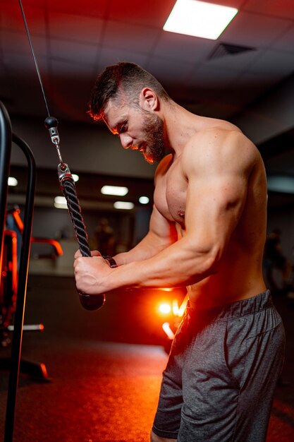 Foto il bodybuilder bello si allena spingendo verso l'alto l'esercizio in palestra maschio senza camicia con muscoli forti primo piano