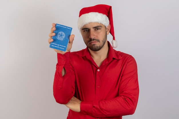 Handsome boy in Christmas clothes and Santa hat holding a Brazilian work card Concept of temporary jobs for the end of the year