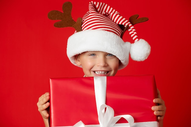 Handsome boy in a funny hat with happy eyes smiles and rejoices at the gift