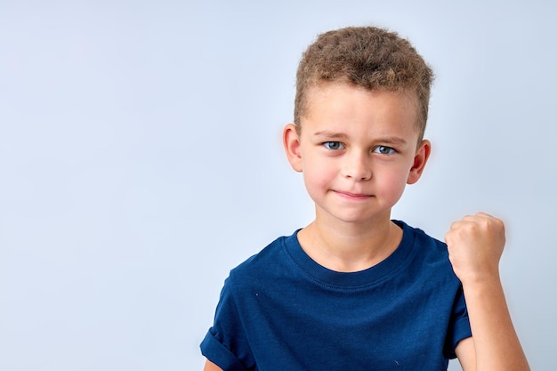 Handsome boy looks angry the child is offended threatens shows a fist angry resentful aggressive chi...